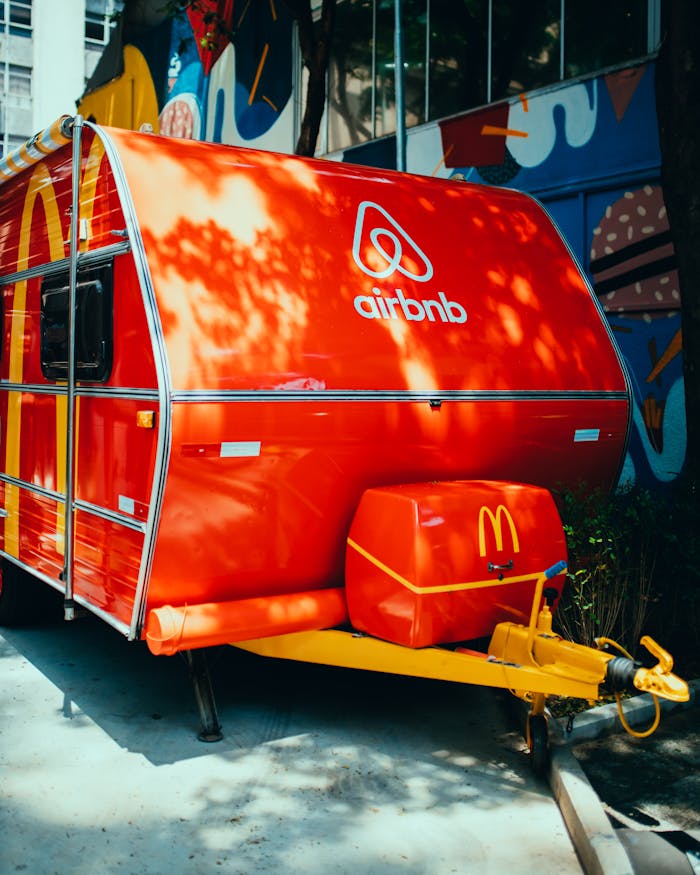 Brightly painted Airbnb branded food truck parked in a vibrant urban area with street art backdrop.